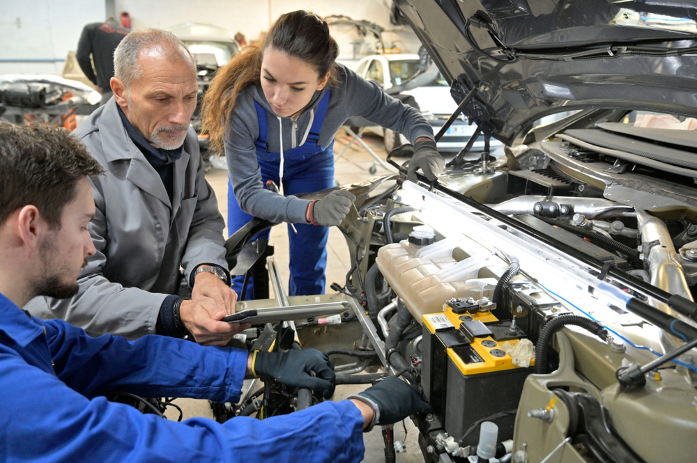 Instructor and students work on a car engine