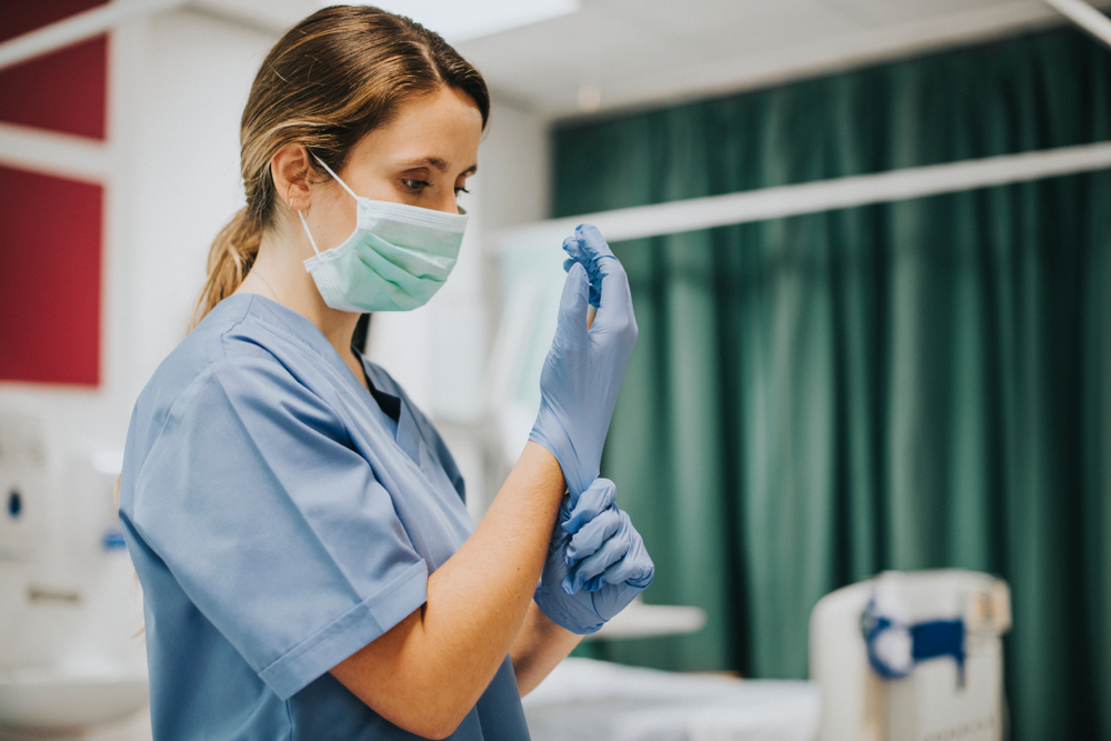 Nurse wearing a mask puts on sterile gloves