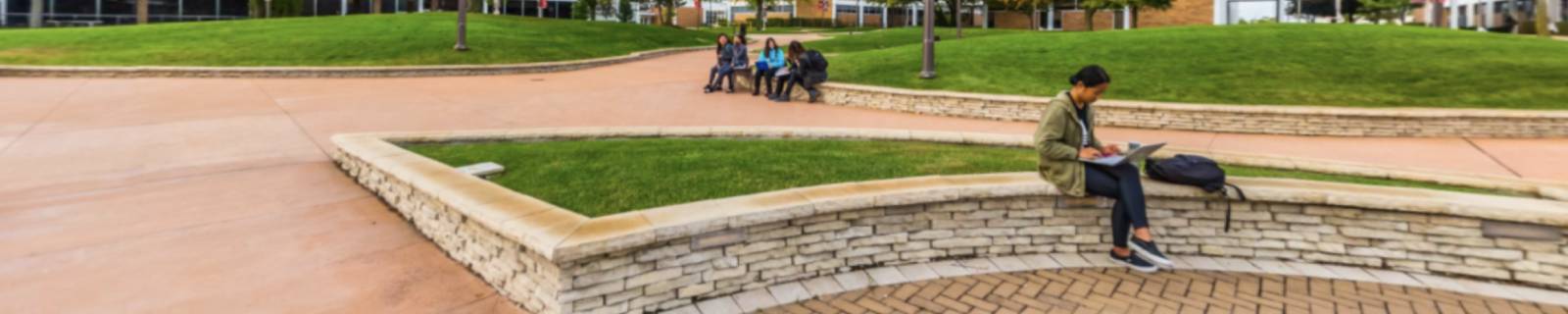 A student sits outside on a ledge on the Triton College campus.