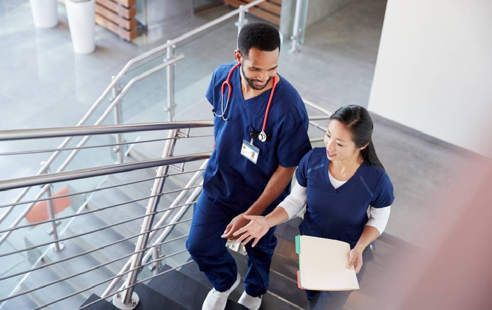 Two healthcare professionals walk together up a staircase.