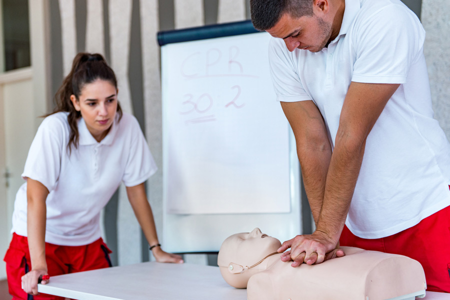 Student in CPR class demonstrates technique while instructor watches