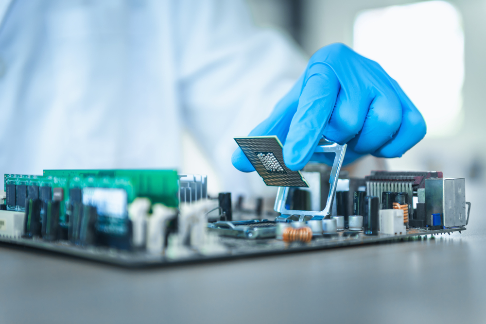 Blue gloved hand holds the central processing unit, or CPU, of a computer, example of electronic technician training