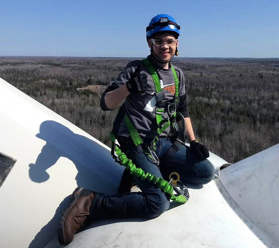 Charlie Tran gives a thumbs up on top of a wind turbine