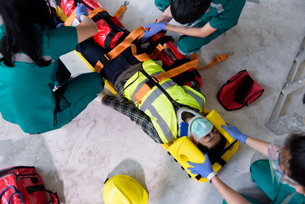 Young emergency workers tend to a man strapped to a backboard