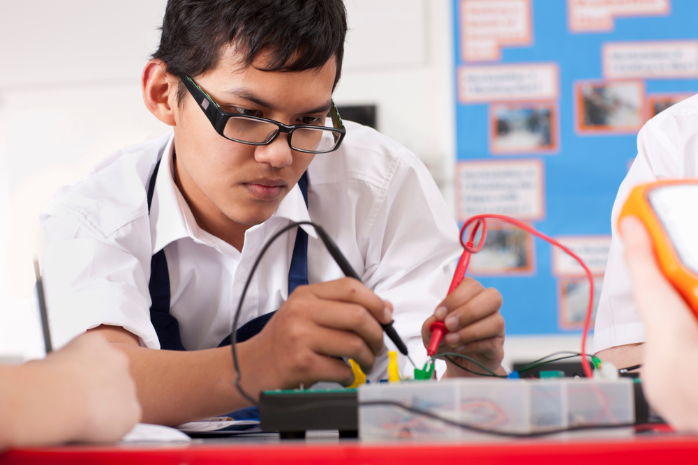 Student in electronics trade school program works on electronics board