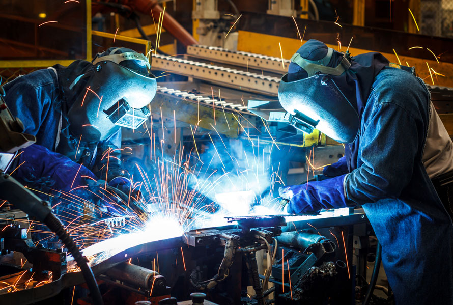 Two welders with helmets learn how to weld. Importance of finding a good trade school program