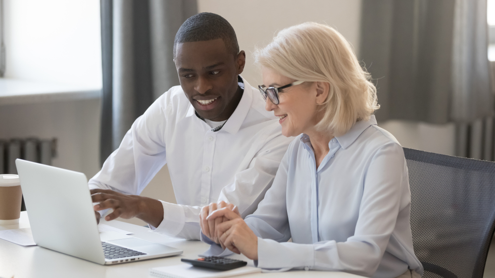 Young black IT support specialist shows older woman computer solution