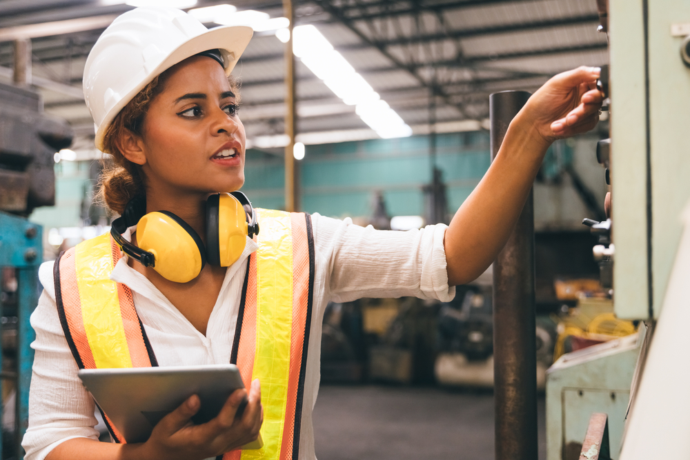 woman inspects a protection system on machinery in a factory setting