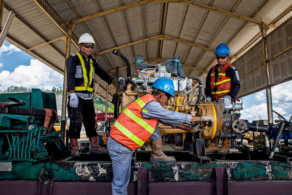 Diesel technicians in safety gear do routine engine maintenance on a machine used for mining