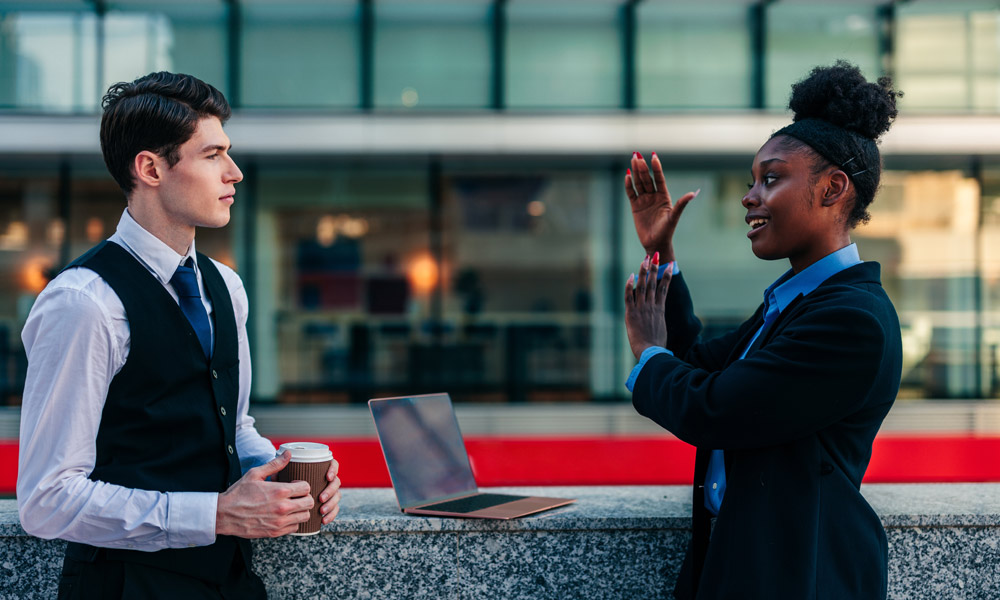 Young African American businesswoman talks to her Caucasian coworker over a cup of coffee