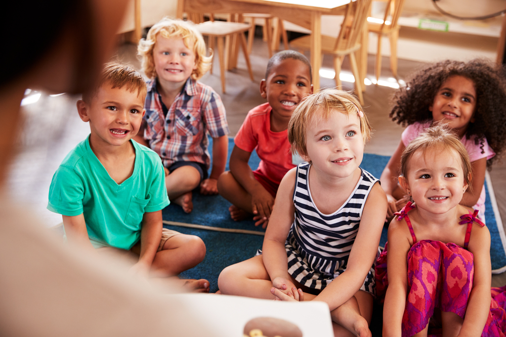 Young kids listen to a teacher in a classroom, representing public service jobs in Phoenix