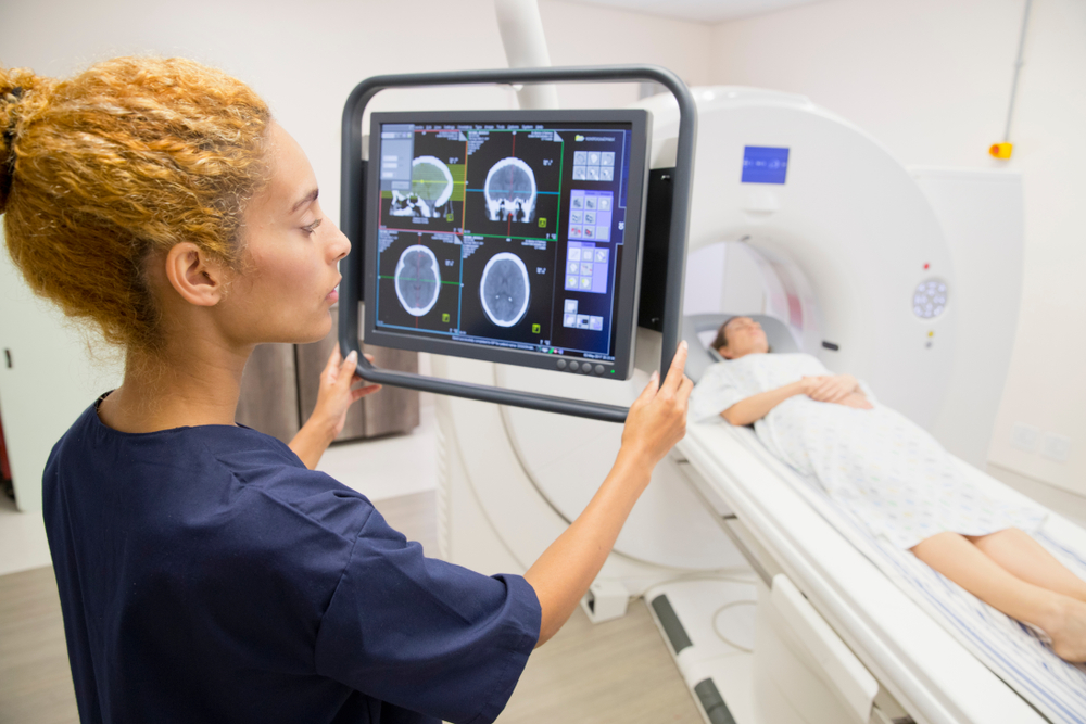 Female radiologist technician operating CT scanner with female patient. Radiology techs are among the highest paying skilled trade jobs