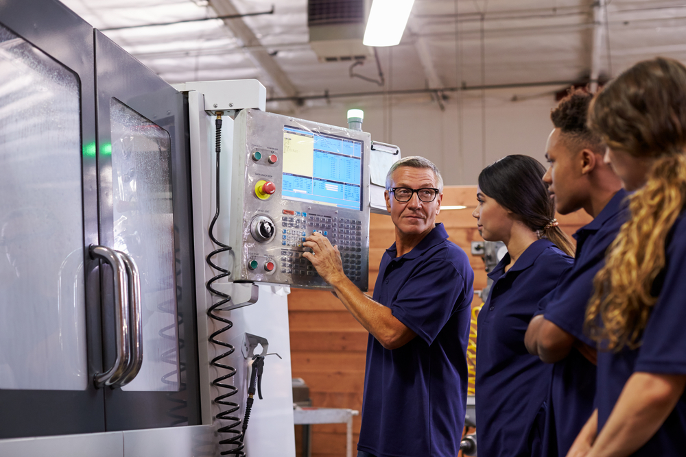 Engineer training apprentices on CNC machine, importance of reskilling