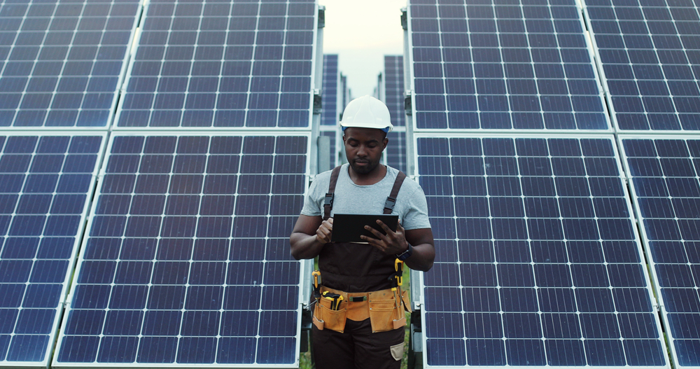 Technician at solar farm with tablet