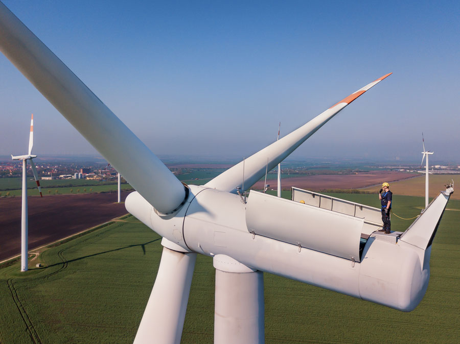 Wind turbine tech stands on top of a wind turbine with gorgeous view of the countryside
