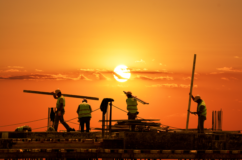Sun sets over a construction site with infrastructure workers doing their jobs