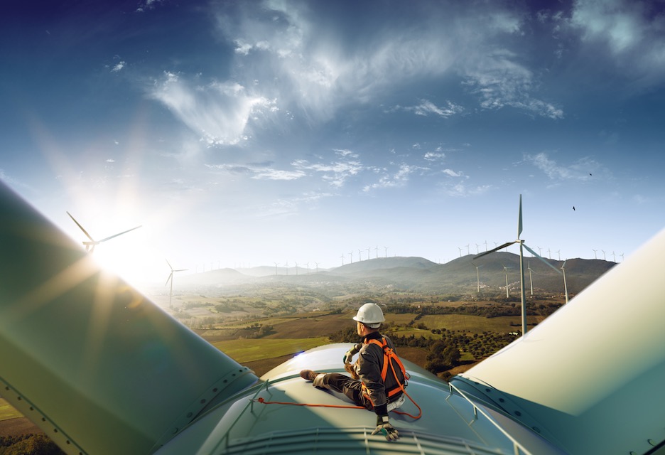 Wind turbine technician sitting on top of a wind turbine enjoying the view