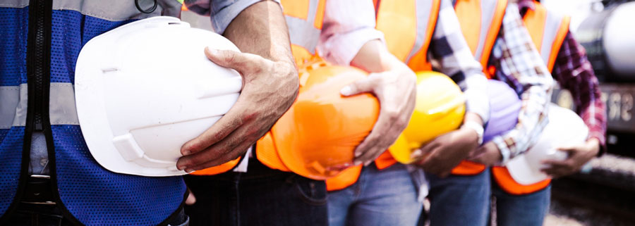 construction workers in safety vests hold their helmets 