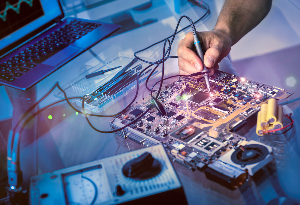 Hand of an electronic technician fixes a circuit board, example of electrical technician training