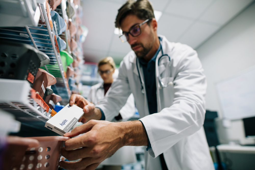 male and female pharmacy technicians organize items on pharmacy shelves