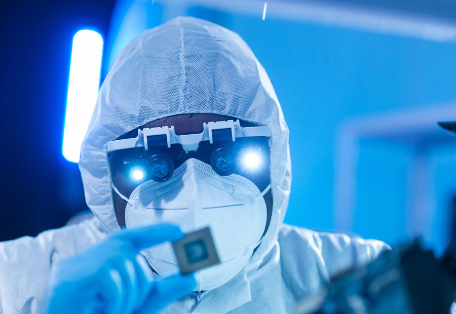 worker in semiconductor manufacturing plant uses special glasses to study the details of a microchip