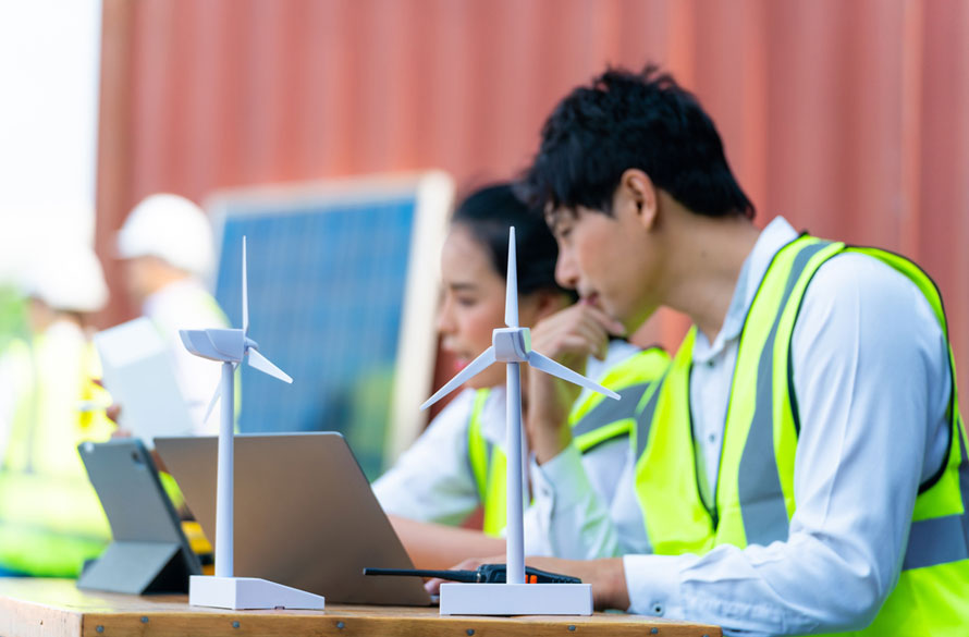 Young wind turbine technicians look at a scaled model. Example of associate degree jobs that are often overlooked.