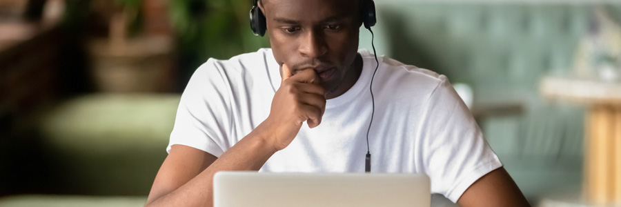 Young black man studies on a laptop with headphones on