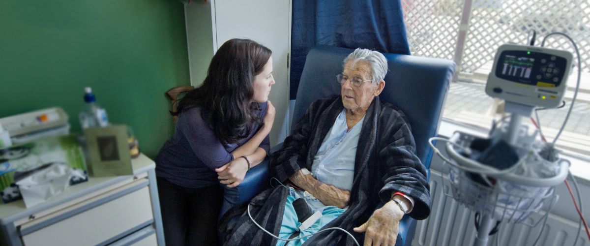 A social services assistant checks on an elderly client in a medical setting