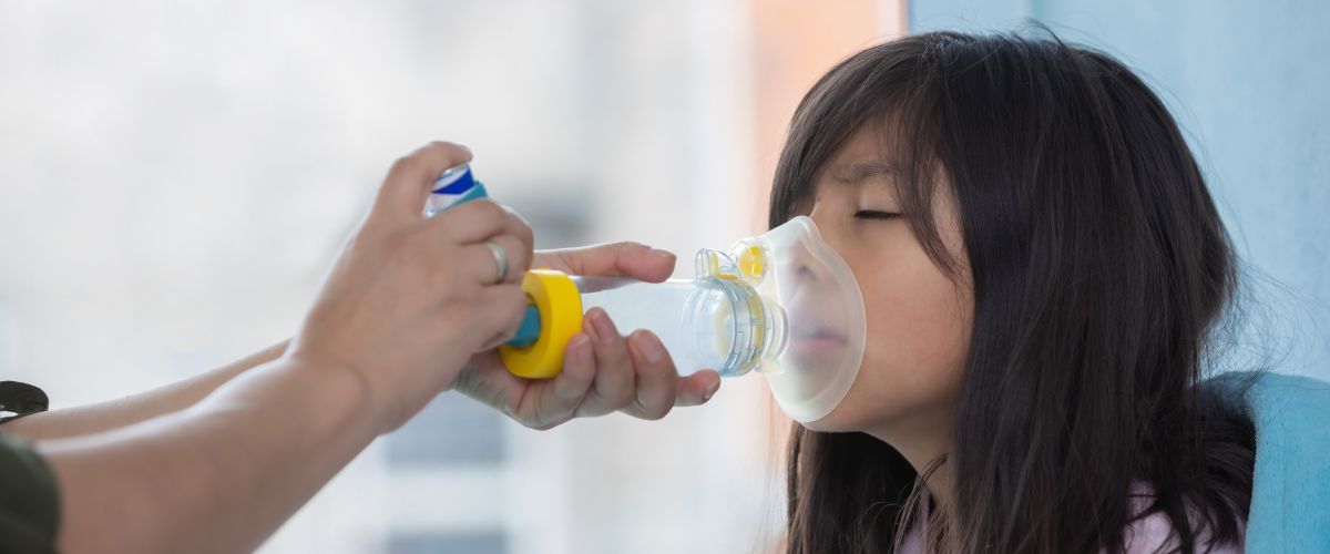 Respiratory therapist uses an inhaler to help a young girl experiencing breathing problems