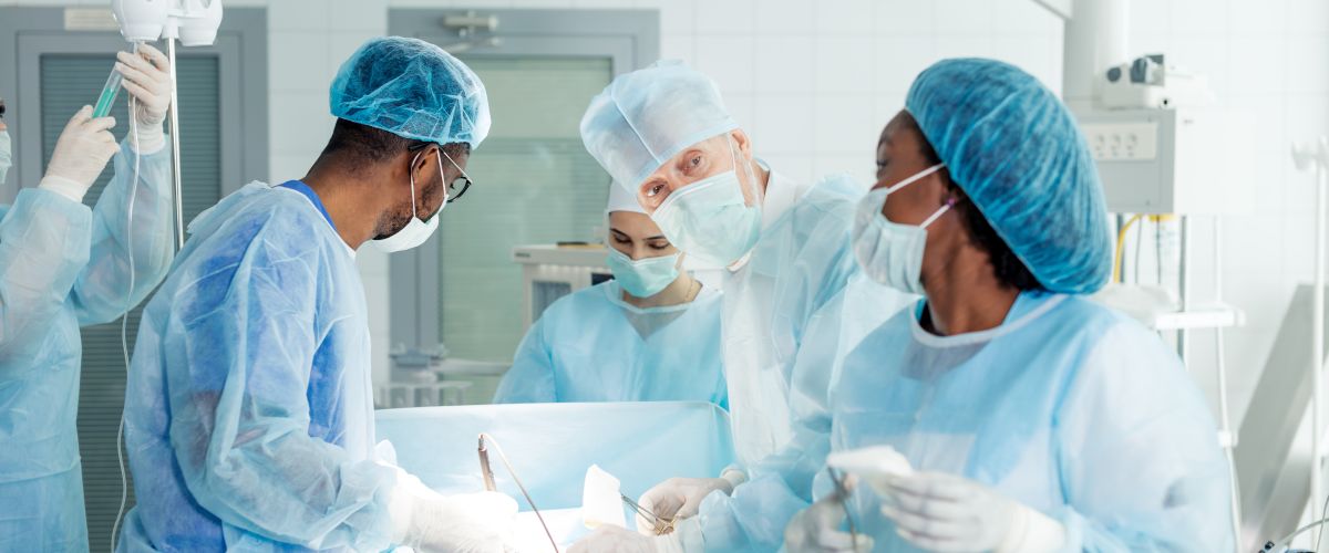 A surgical tech assists a doctor with a patient by an operating table