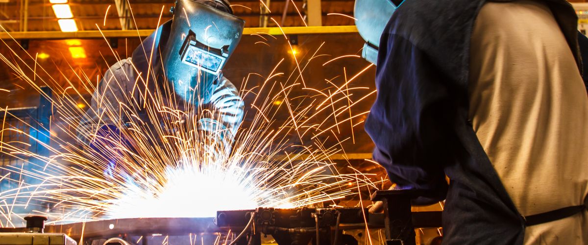 Two welders cut metal in an automotive factory