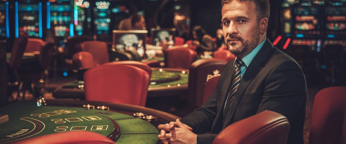 Male casino manager in a suit sits at a gaming table in a casino