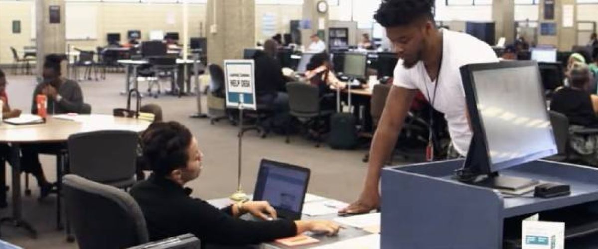 Students at Cuyahoga Community College work on computers and speak with eachother.