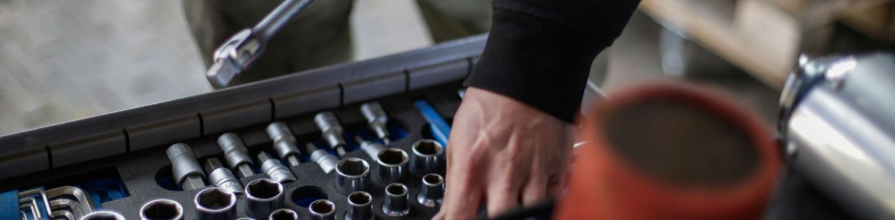 Mechanic's hands selecting socket wrench from toolkit in workshop setting.