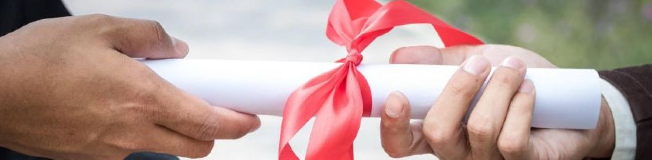 Two hands holding a rolled piece of white paper wrapped in a red ribbon.