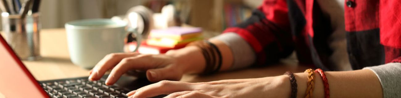 Close up of teenage girl's hands as she works on a laptop. Example of looking for trade school scholarships and how they support young people trying to explore skills-based jobs. 