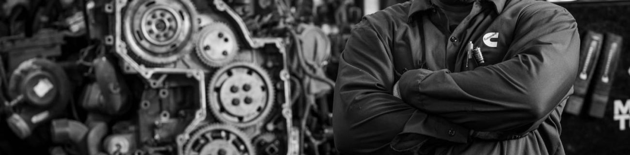 black and white photo of a proud Cummins technician with a machine in the background
