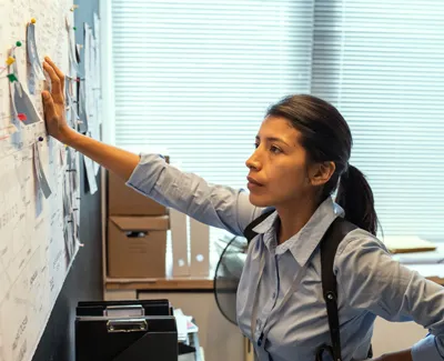 female criminal investigator looks at the case board