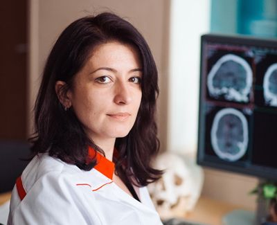 MRI technician in front of a screen with scan