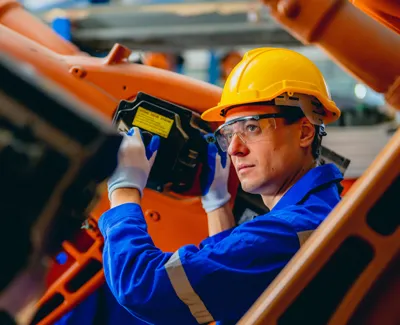 Robotics or electro-mechanical technician works on a factory machine