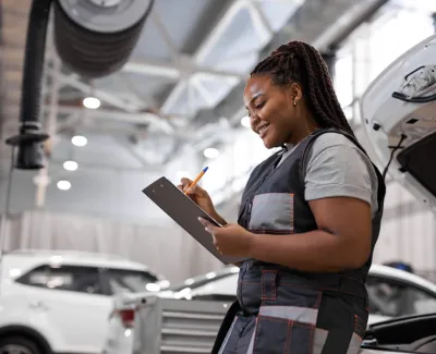 Female mechanic leaning against car