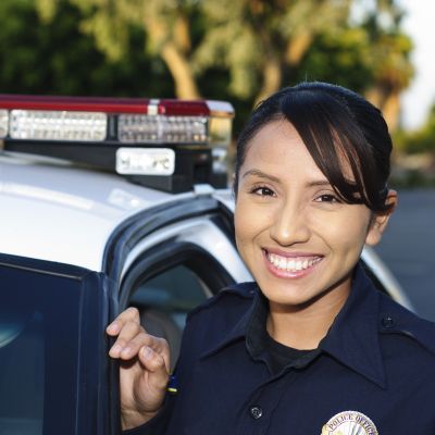 Female police officer stands by her patrol car