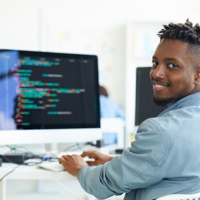 A software developer sits at a computer and writes code