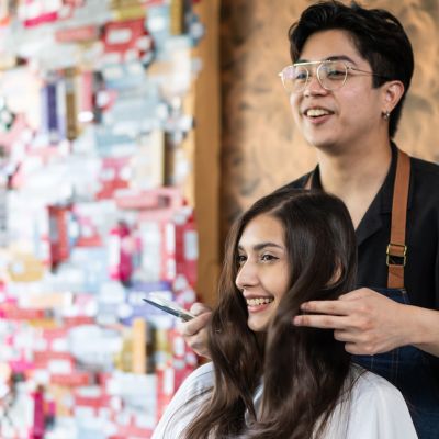 Young Asian hairdresser styles a young woman's hair at a salon