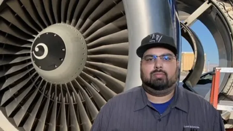 Lorenzo Carlos Perez, aircraft mechanic ambassador, in front of an airplane engine