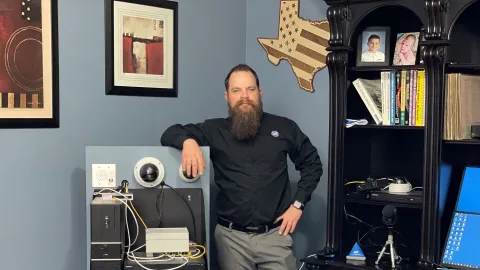 Casey Williams, security alarm technician trainer, stands by a security system in ADT offices