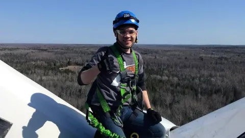 Charlie Tran, wind turbine technician ambassador, gives the thumbs-up on top of a wind turbine