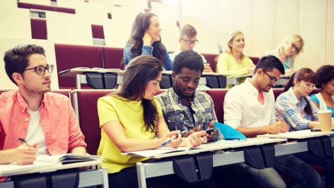 Community college students take notes and listen to the instructor in a classroom