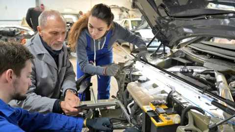 Instructor and two students work on a car during training