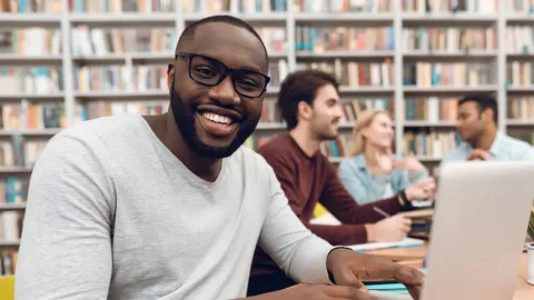 Young Black man works on a laptop in the library, doing financial aid research
